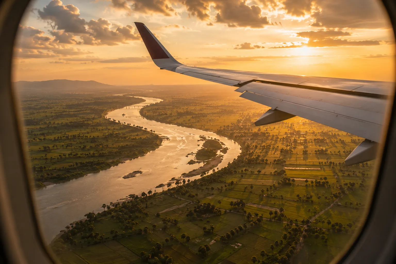 Aile d'avion au-dessus des rizières et méandres du Cambodge